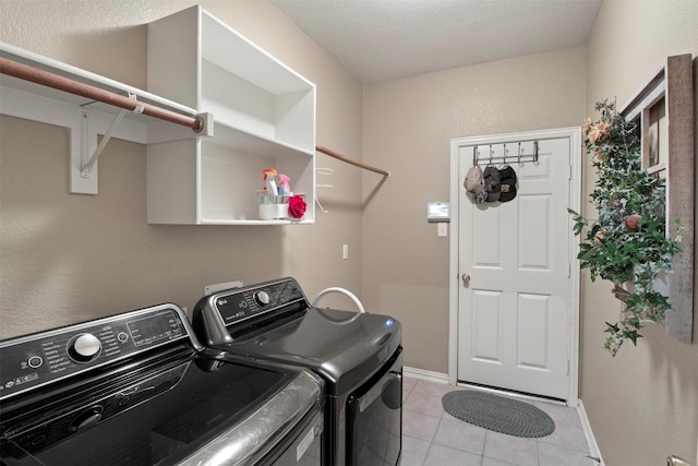 clothes washing area featuring light tile patterned floors, laundry area, independent washer and dryer, and baseboards