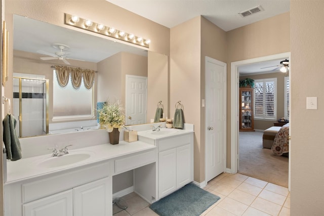 ensuite bathroom featuring tile patterned floors, visible vents, ceiling fan, and a sink