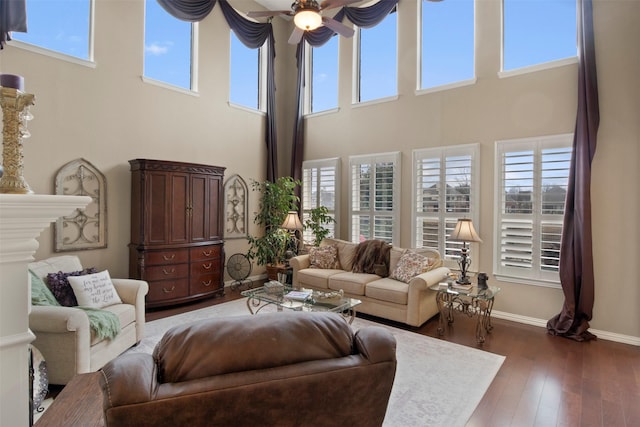 living room with ceiling fan, baseboards, and dark wood-style floors