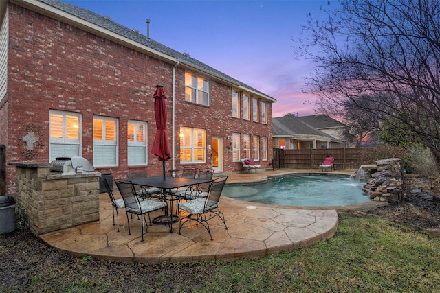 view of swimming pool featuring a patio area, fence, a fenced in pool, and an outdoor kitchen