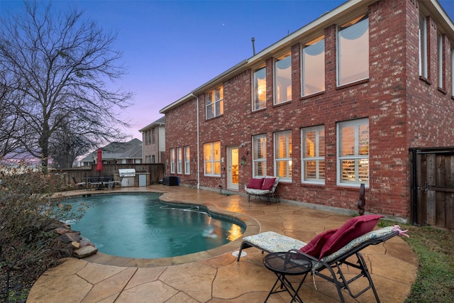 pool at dusk with a patio area, grilling area, a fenced in pool, and fence