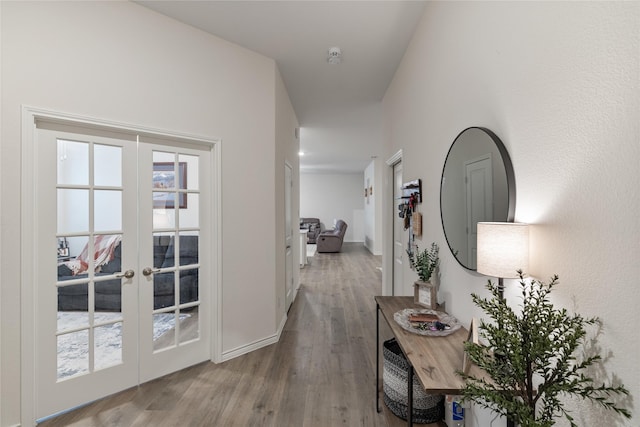 corridor with french doors and light hardwood / wood-style flooring