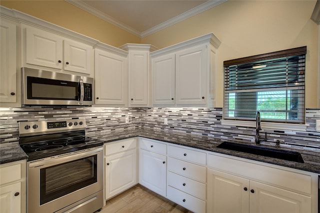 kitchen with white cabinetry, stainless steel appliances, sink, and dark stone counters