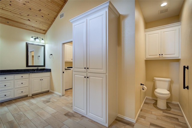 bathroom featuring lofted ceiling, toilet, washer / dryer, vanity, and hardwood / wood-style flooring