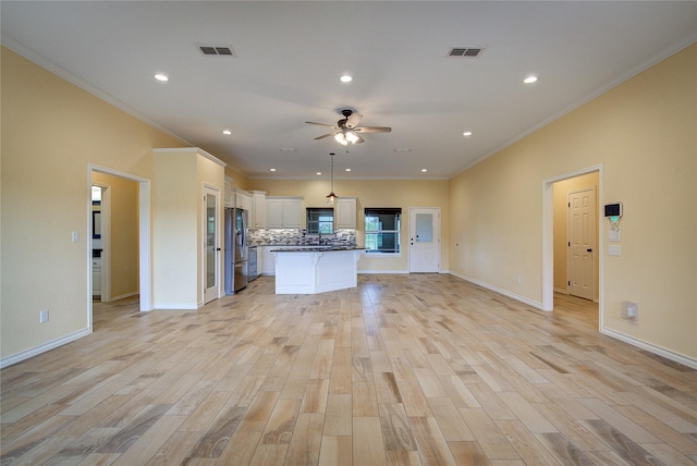 kitchen featuring stainless steel fridge, white cabinetry, a kitchen island, decorative backsplash, and light wood-type flooring