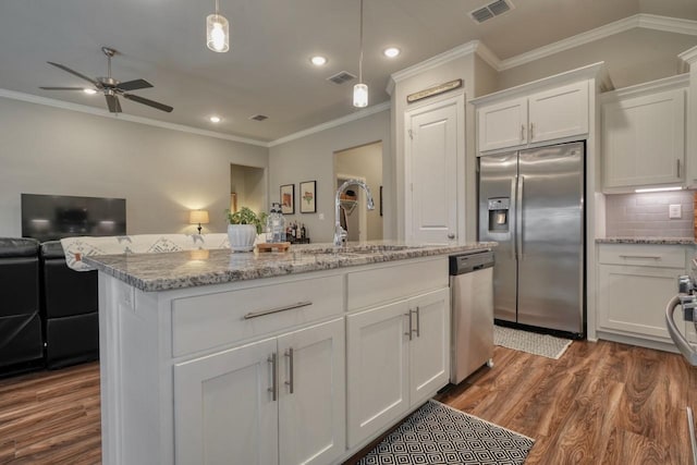 kitchen featuring white cabinetry, light stone counters, decorative light fixtures, a center island with sink, and appliances with stainless steel finishes