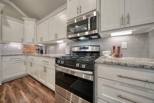 kitchen featuring appliances with stainless steel finishes, white cabinetry, decorative backsplash, light stone counters, and dark wood-type flooring