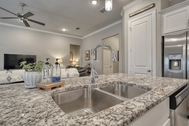 kitchen with sink, crown molding, stainless steel appliances, light stone countertops, and white cabinets