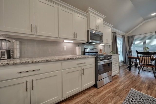 kitchen featuring lofted ceiling, white cabinetry, stainless steel appliances, tasteful backsplash, and light hardwood / wood-style floors