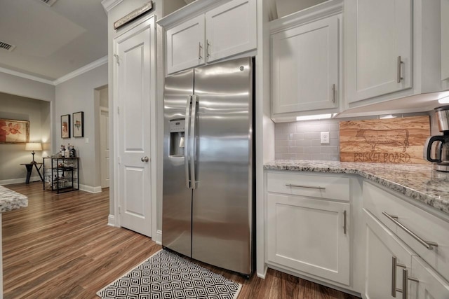 kitchen featuring crown molding, stainless steel fridge with ice dispenser, tasteful backsplash, and white cabinets