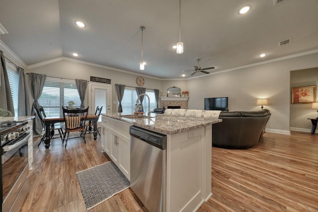 kitchen featuring sink, appliances with stainless steel finishes, a kitchen island with sink, hanging light fixtures, and white cabinets