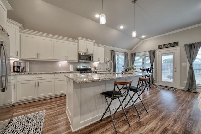 kitchen with white cabinetry, an island with sink, appliances with stainless steel finishes, and decorative light fixtures