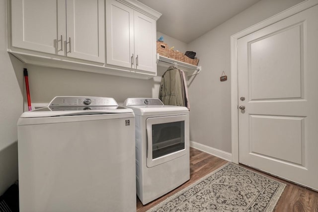 laundry area with separate washer and dryer, dark wood-type flooring, and cabinets