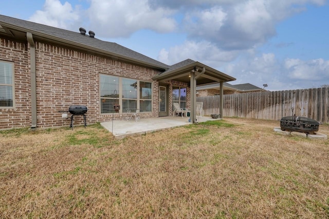 back of property with an outdoor fire pit, a patio area, and a lawn