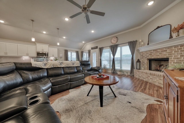 living room featuring crown molding, a fireplace, light hardwood / wood-style floors, and a wealth of natural light