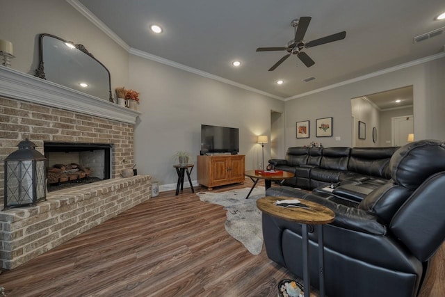 living room with hardwood / wood-style flooring, crown molding, a brick fireplace, and ceiling fan