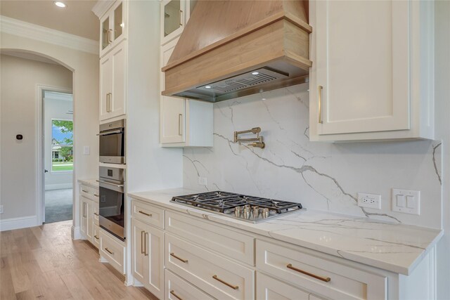 121 Ford Ct, Weston, TX 75009 - kitchen featuring custom exhaust hood, arched walkways, ornamental molding, decorative backsplash, and white cabinetry