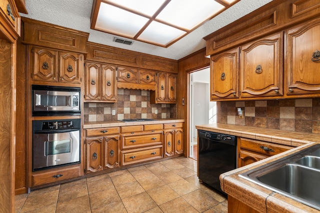 kitchen with stainless steel appliances, tasteful backsplash, sink, and tile countertops