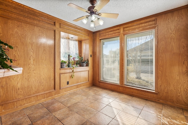 entryway with ceiling fan, a textured ceiling, and wood walls