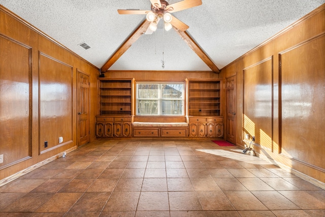 spare room with vaulted ceiling with beams, built in features, a textured ceiling, and wood walls