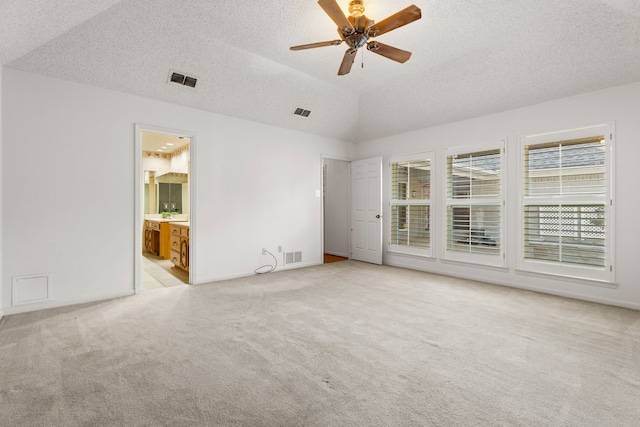 unfurnished bedroom featuring vaulted ceiling, light colored carpet, a textured ceiling, and ensuite bath