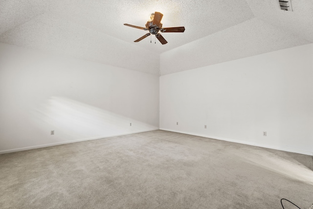 spare room featuring ceiling fan, lofted ceiling, carpet, and a textured ceiling