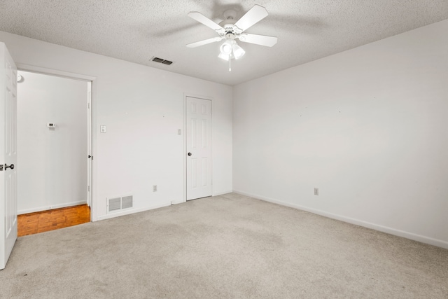 carpeted spare room featuring ceiling fan and a textured ceiling