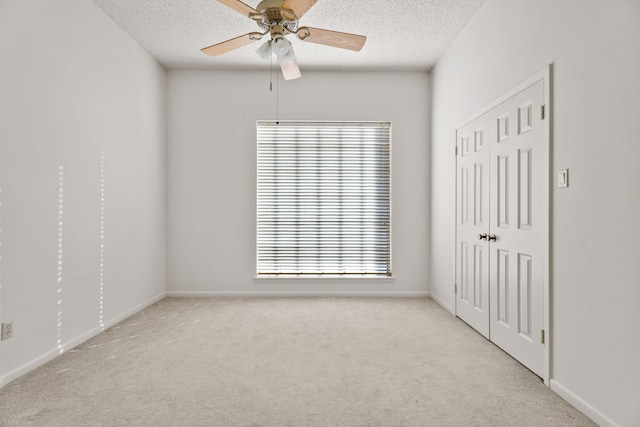 spare room with ceiling fan, light carpet, and a textured ceiling