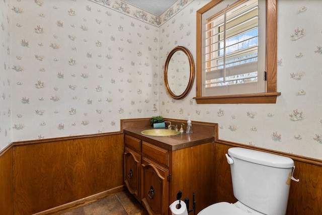 bathroom featuring vanity, wood walls, and toilet