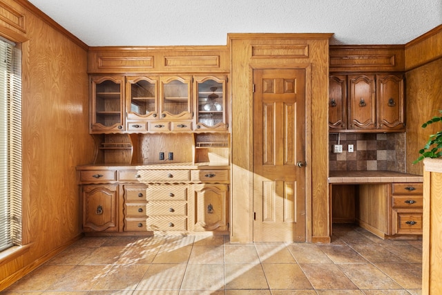 kitchen with ornamental molding, wooden walls, and a textured ceiling