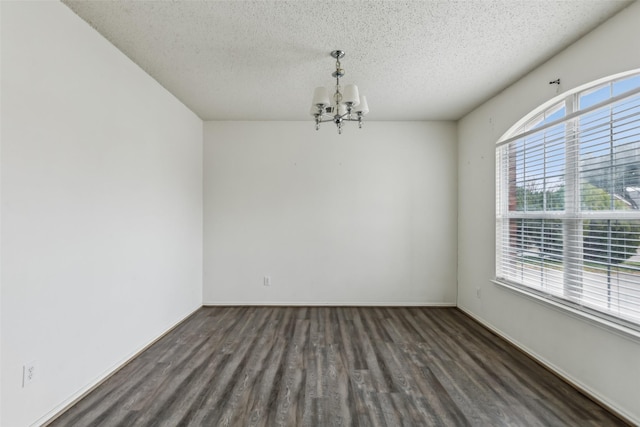 empty room featuring dark hardwood / wood-style floors, a textured ceiling, and a chandelier