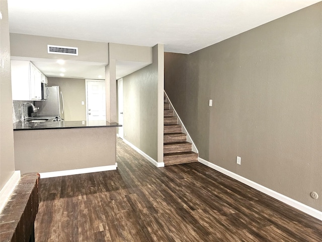 kitchen featuring sink, dark hardwood / wood-style floors, kitchen peninsula, white cabinets, and backsplash