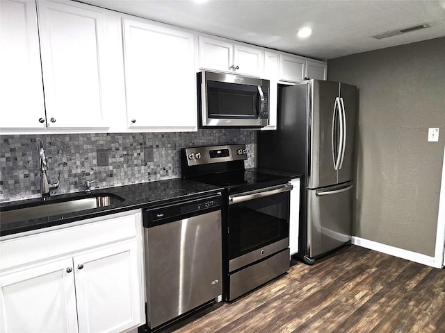 kitchen with dark wood-type flooring, sink, tasteful backsplash, stainless steel appliances, and white cabinets