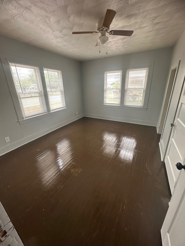 empty room featuring dark hardwood / wood-style flooring, ceiling fan, a wealth of natural light, and a textured ceiling