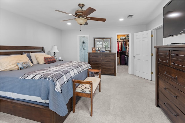 bedroom featuring ensuite bath, a spacious closet, light colored carpet, a closet, and ceiling fan