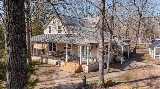 view of front of home featuring metal roof, a porch, a standing seam roof, and driveway