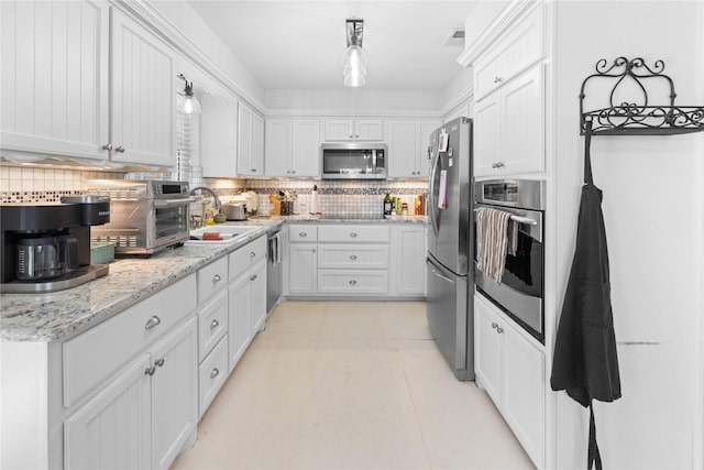 kitchen featuring pendant lighting, decorative backsplash, white cabinets, and appliances with stainless steel finishes