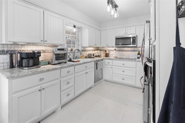 kitchen with sink, decorative backsplash, white cabinets, and appliances with stainless steel finishes