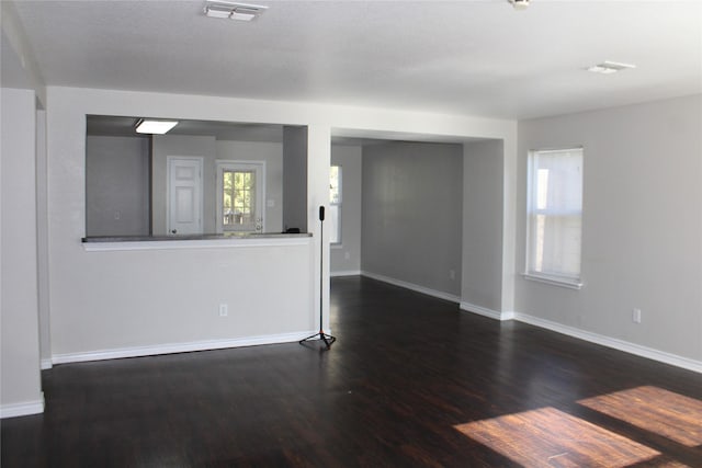 unfurnished living room featuring dark hardwood / wood-style flooring and a healthy amount of sunlight