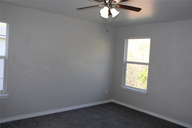 spare room featuring ceiling fan and dark colored carpet