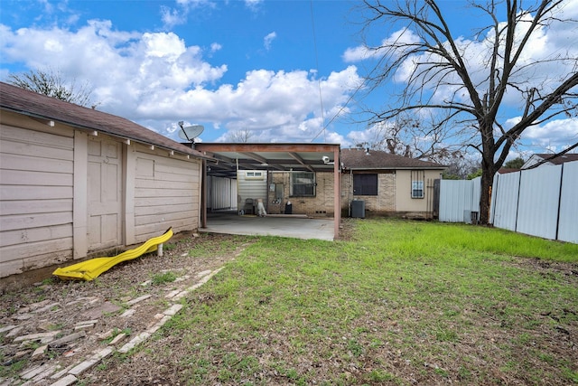 rear view of house with a patio, central AC, and a lawn