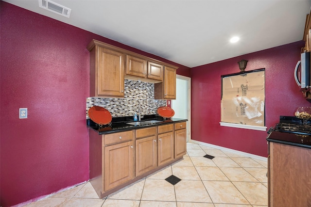 kitchen featuring sink, light tile patterned floors, dark stone counters, and decorative backsplash