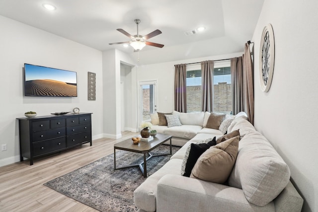 living room featuring a ceiling fan, light wood-type flooring, visible vents, and baseboards