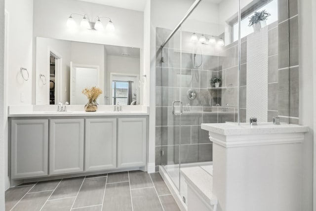 full bathroom featuring a stall shower, a healthy amount of sunlight, and double vanity