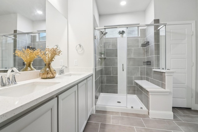 bathroom with tile patterned flooring, a sink, a shower stall, and double vanity