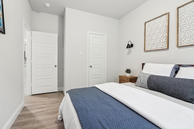 bedroom featuring light wood finished floors and baseboards