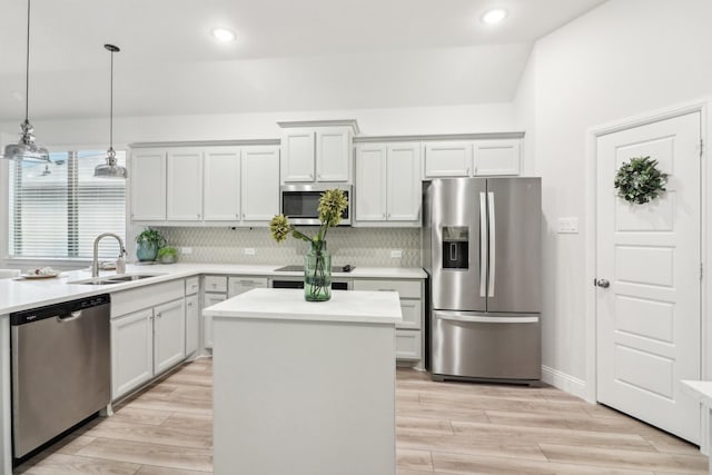 kitchen featuring pendant lighting, light countertops, appliances with stainless steel finishes, a sink, and a kitchen island