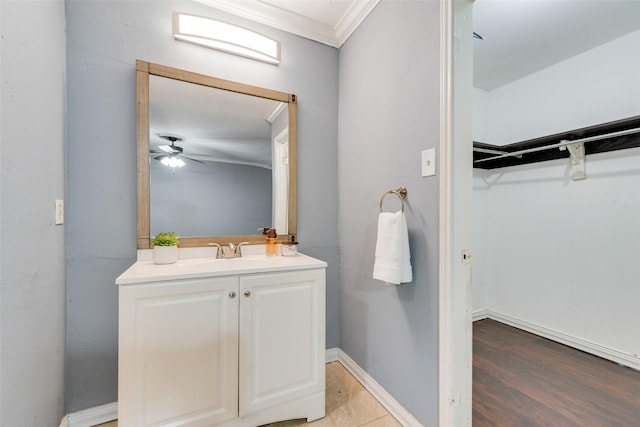 bathroom featuring ornamental molding, ceiling fan, vanity, wood finished floors, and baseboards