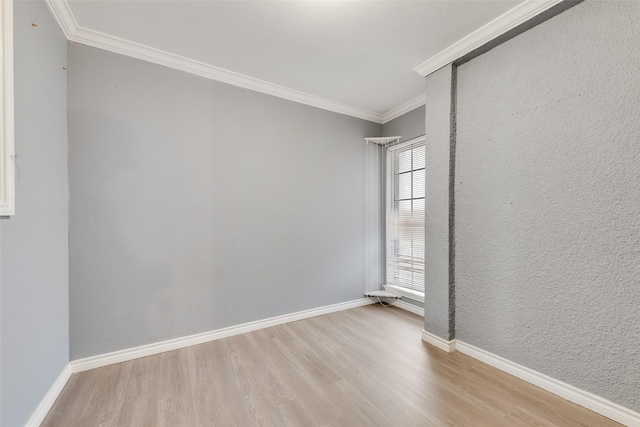 empty room with baseboards, light wood-type flooring, and crown molding