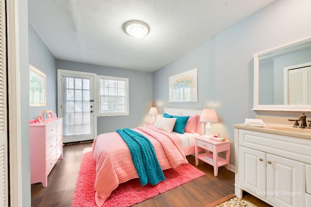 bedroom featuring a sink, dark wood finished floors, and access to exterior